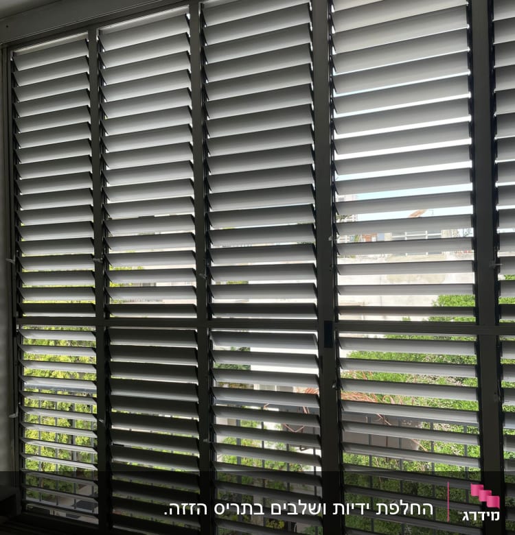 תריסים אופקיים אפורים על חלון גדול